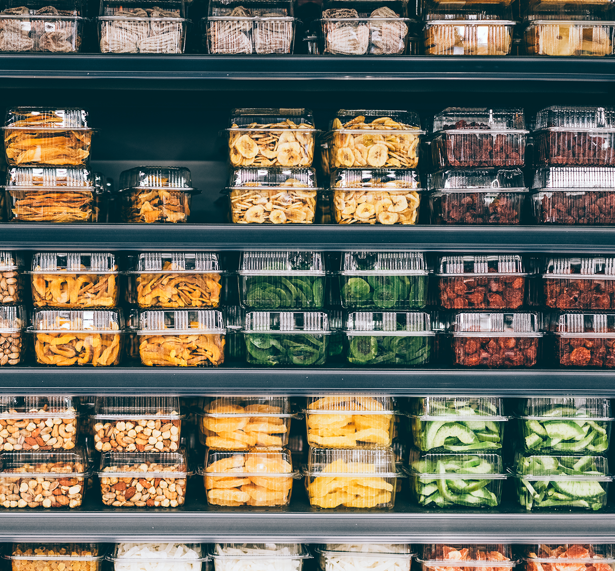 Store shelves with dried fruit, veggies, and nuts in a non-ecological packaging, non-branded. An image of plastic usage everywhere. Taking steps to a more sustainable lifestyle by utilizing reusable packaging and responsible business ideas.