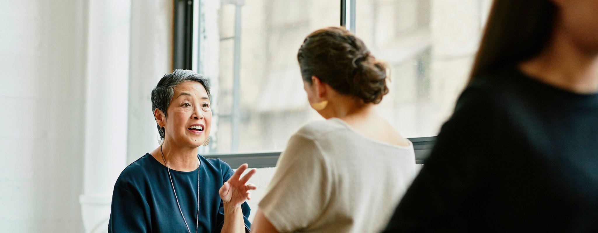 Two women talking in an office breakroom.