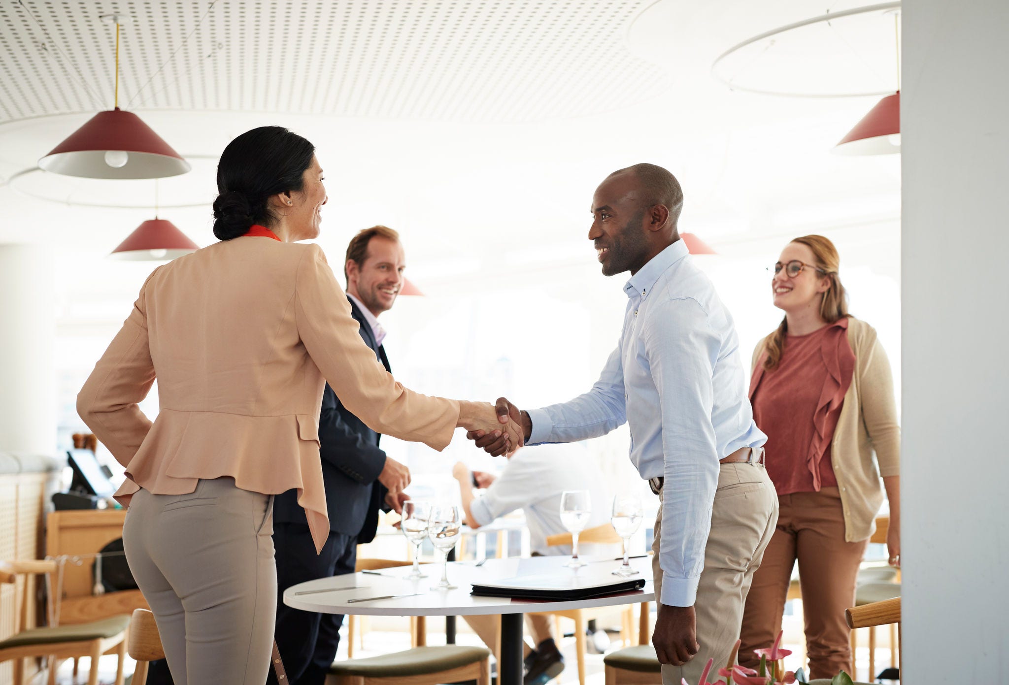 Business people enjoy a casual meeting at a restaurant table, finalizing a deal with a handshake.