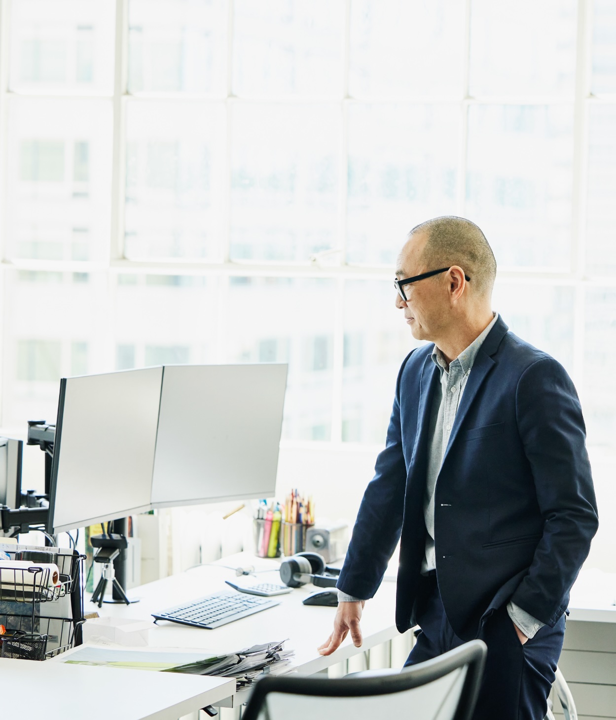 Businessman looks at a pair of computer monitors at his office work desk