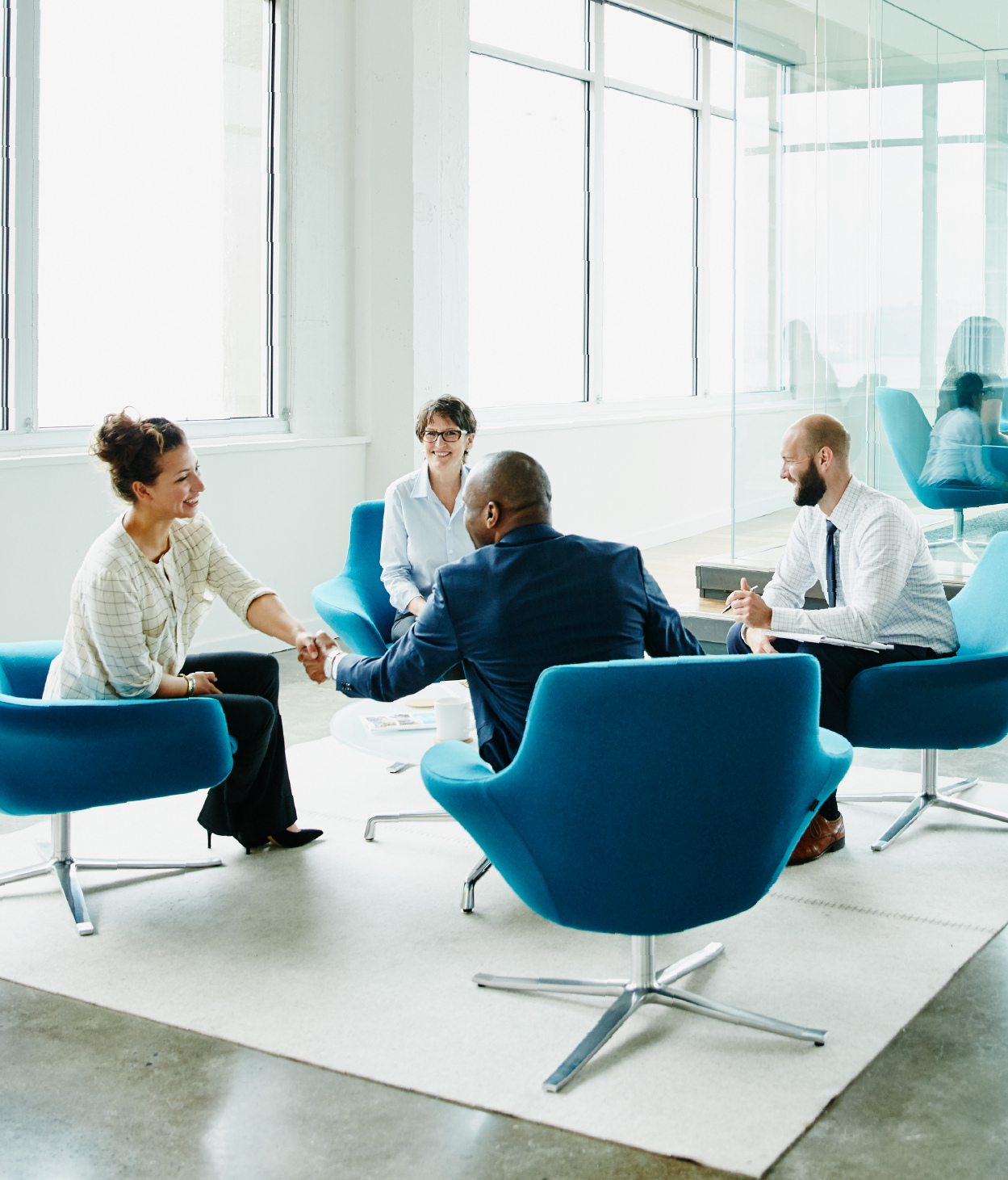 Professionals greet each other at the start of a meeting.